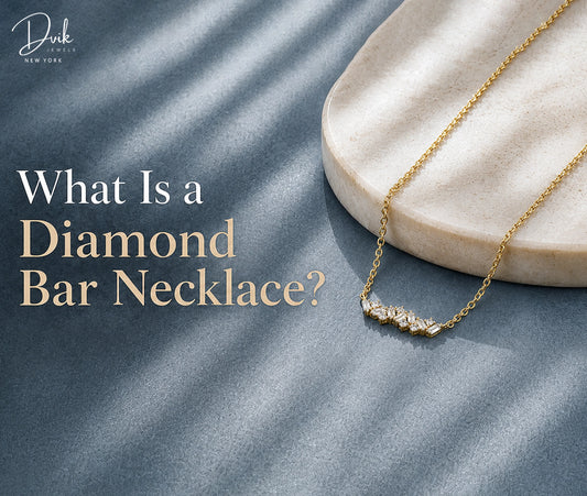 Yellow gold diamond bar necklace styled by Dvik Jewels on a blue textured background, displayed with a round stone jewelry tray.