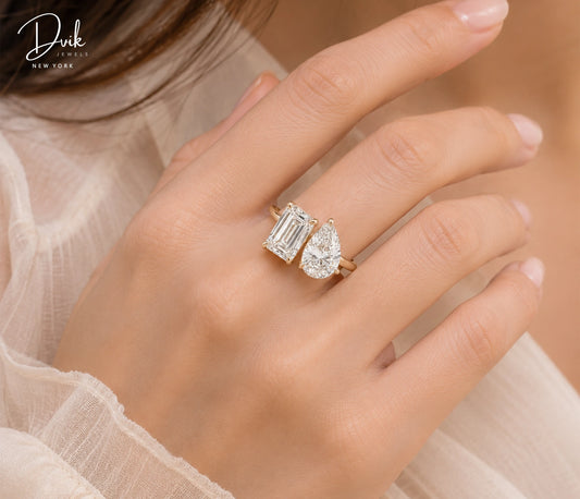 Two stone Toi et Moi engagement ring featuring emerald cut and pear shape diamonds on a yellow gold band by Dvik Jewels.
