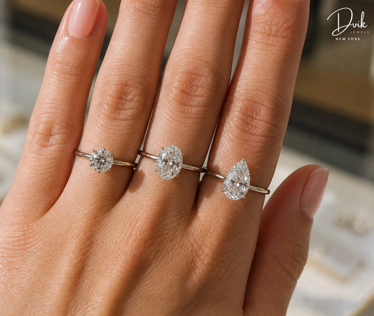 Size comparison of round, oval, and pear-shaped diamond solitaire rings on a hand by Dvik Jewels New York.