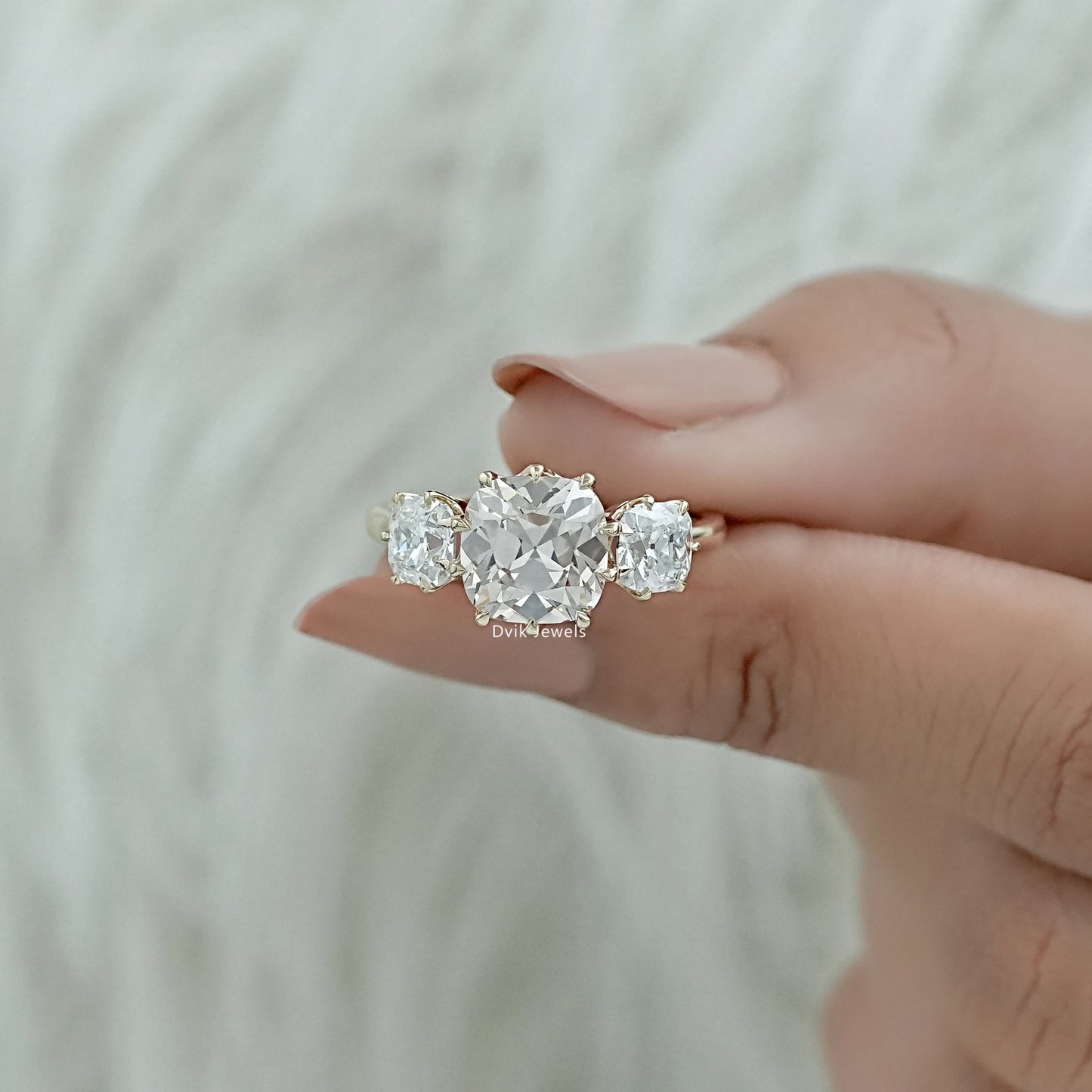 Three-stone anniversary rings held to showcase the classic bridal design