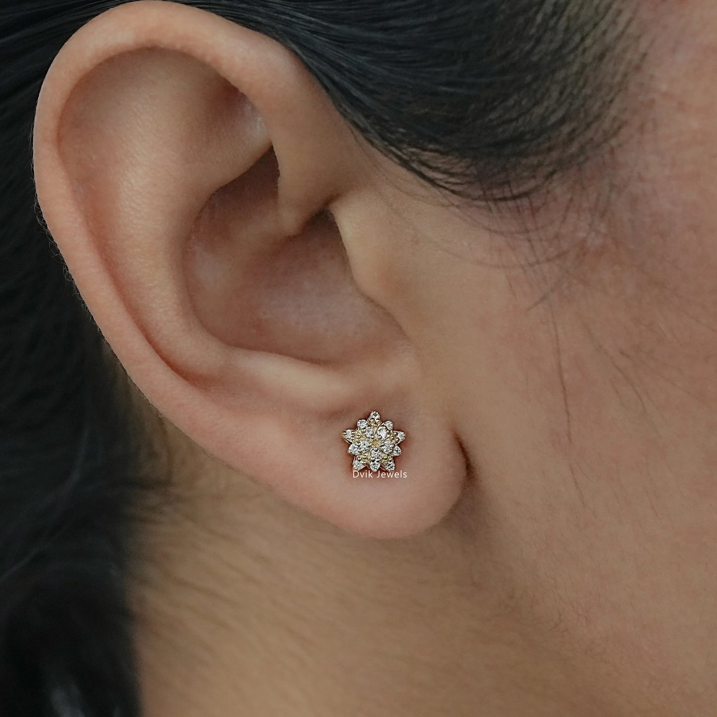 Round diamond stud earrings with floral shape in yellow gold worn by women