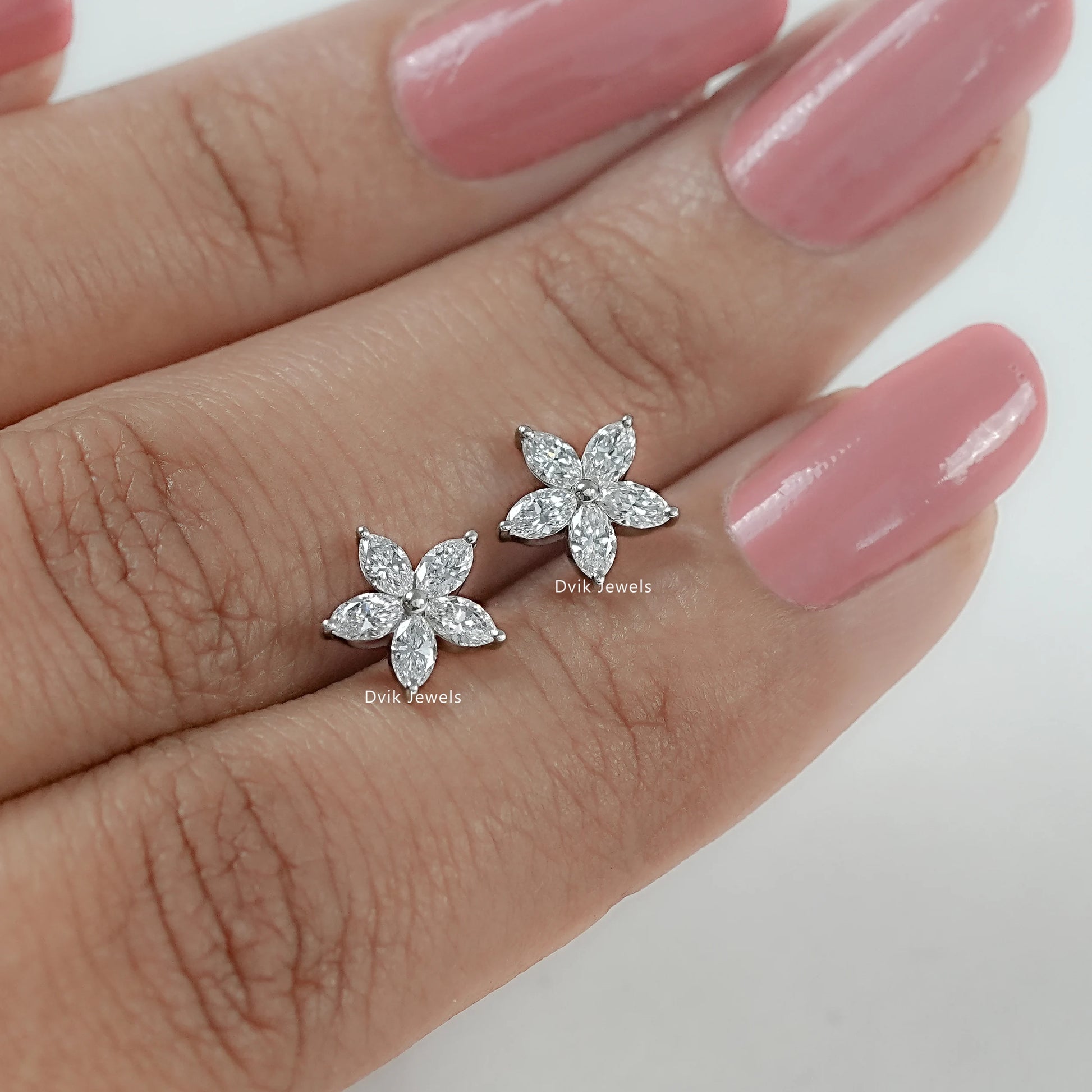 Floral earrings studs with marquise cut diamond held between women’s fingers