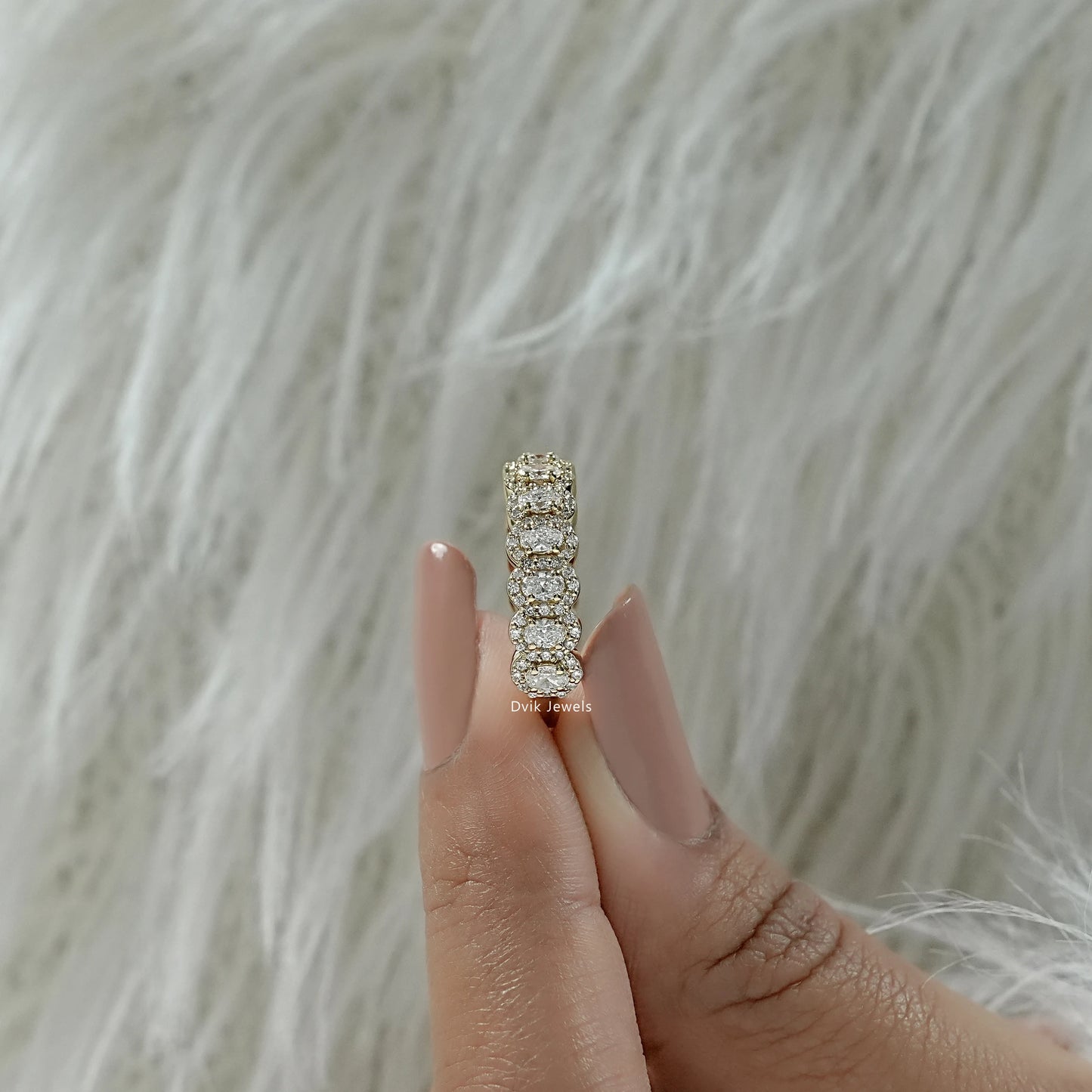 Oval cut eternity band held to show the high-quality gold setting.