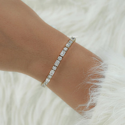 Detailed view of emerald and round diamond tennis bracelet on model hand