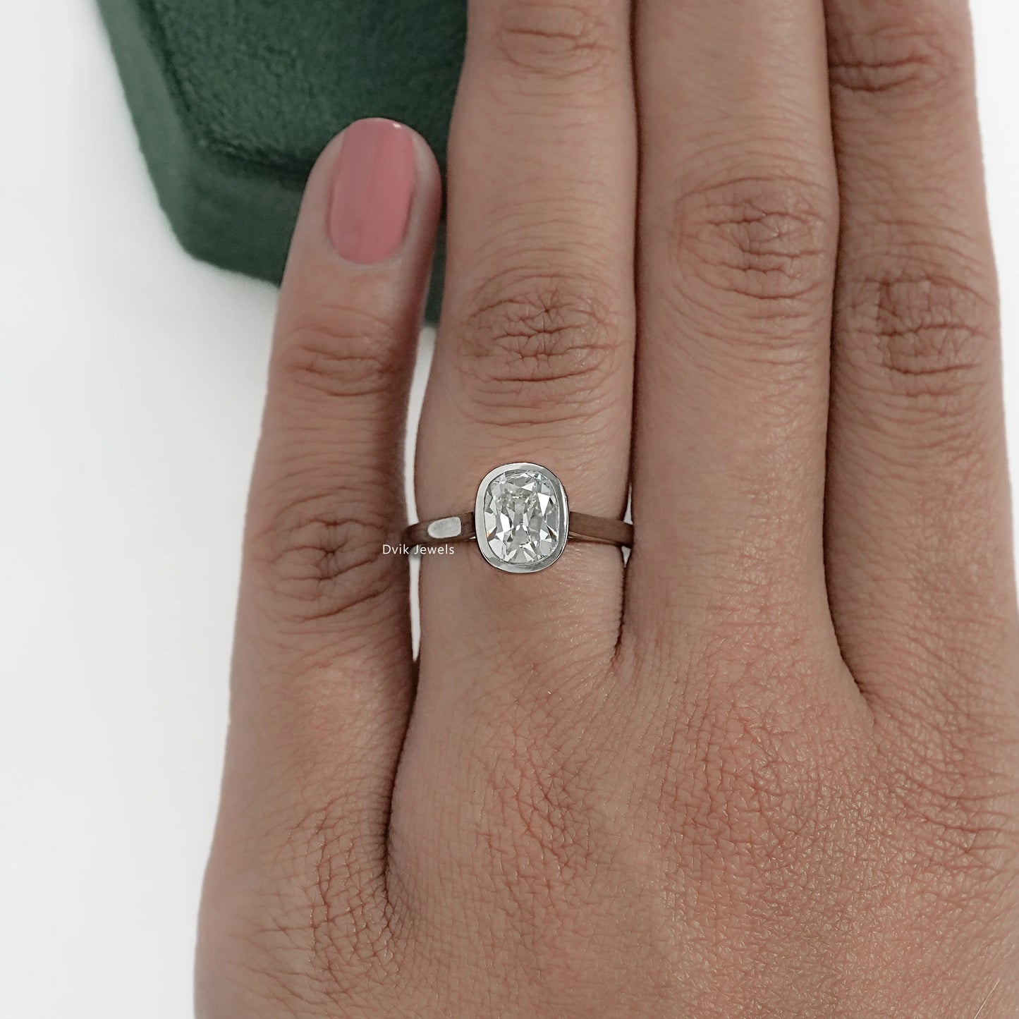 Model hand wearing elongated cushion diamond engagement ring in silver bezel set