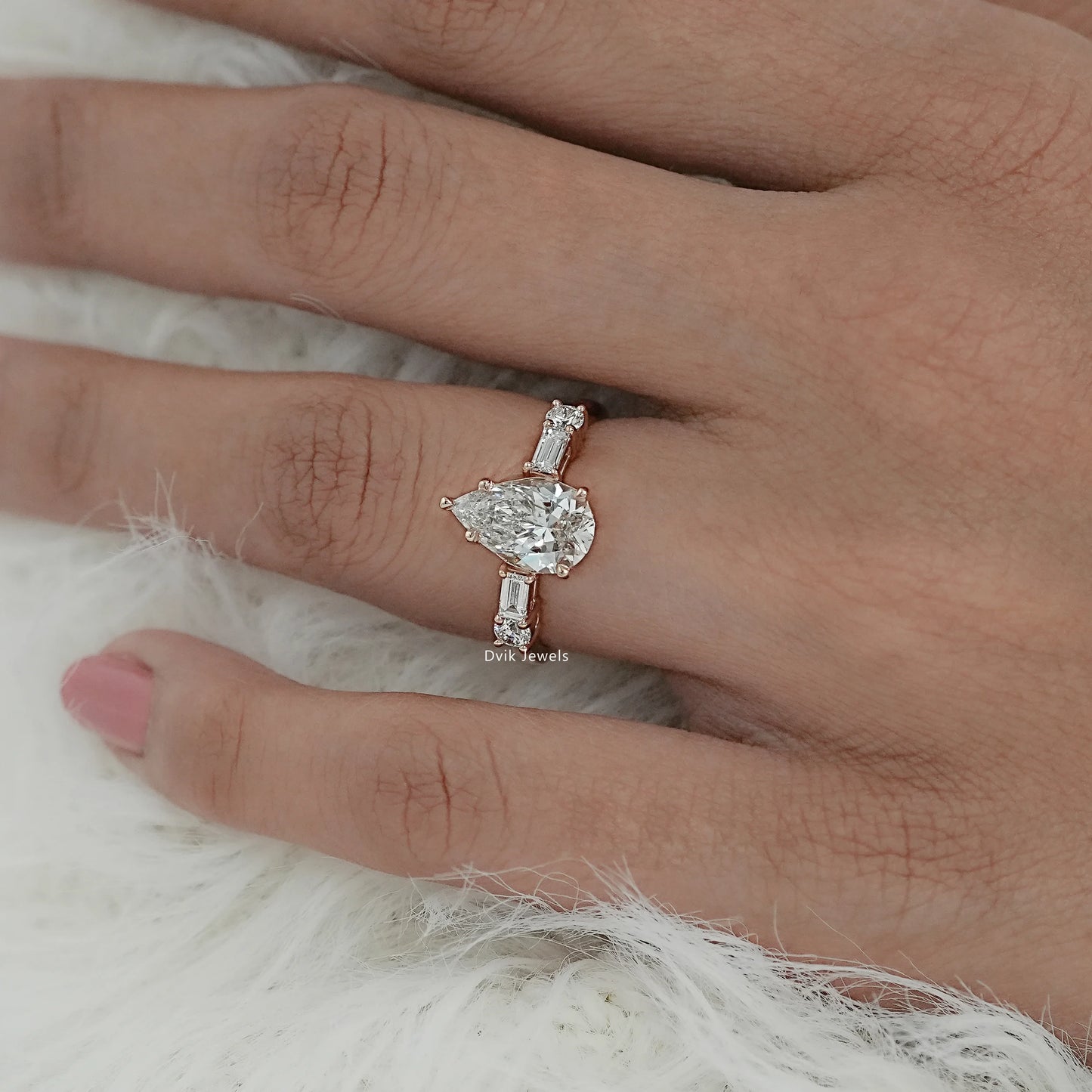 Five stone pear cut engagement ring with baguette diamond on model hand