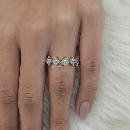Top view of a princess cut diamond ring 2 carat on finger with white fur background.