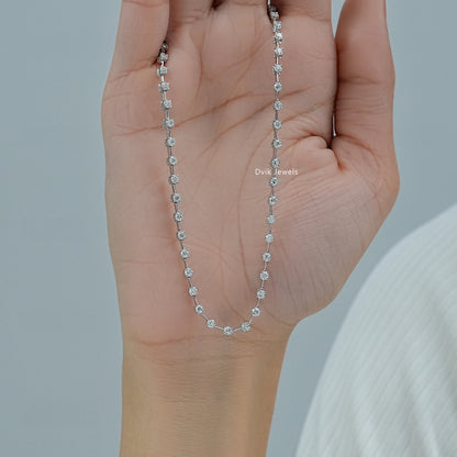 Round diamond station necklace white gold held to show the bezel setting