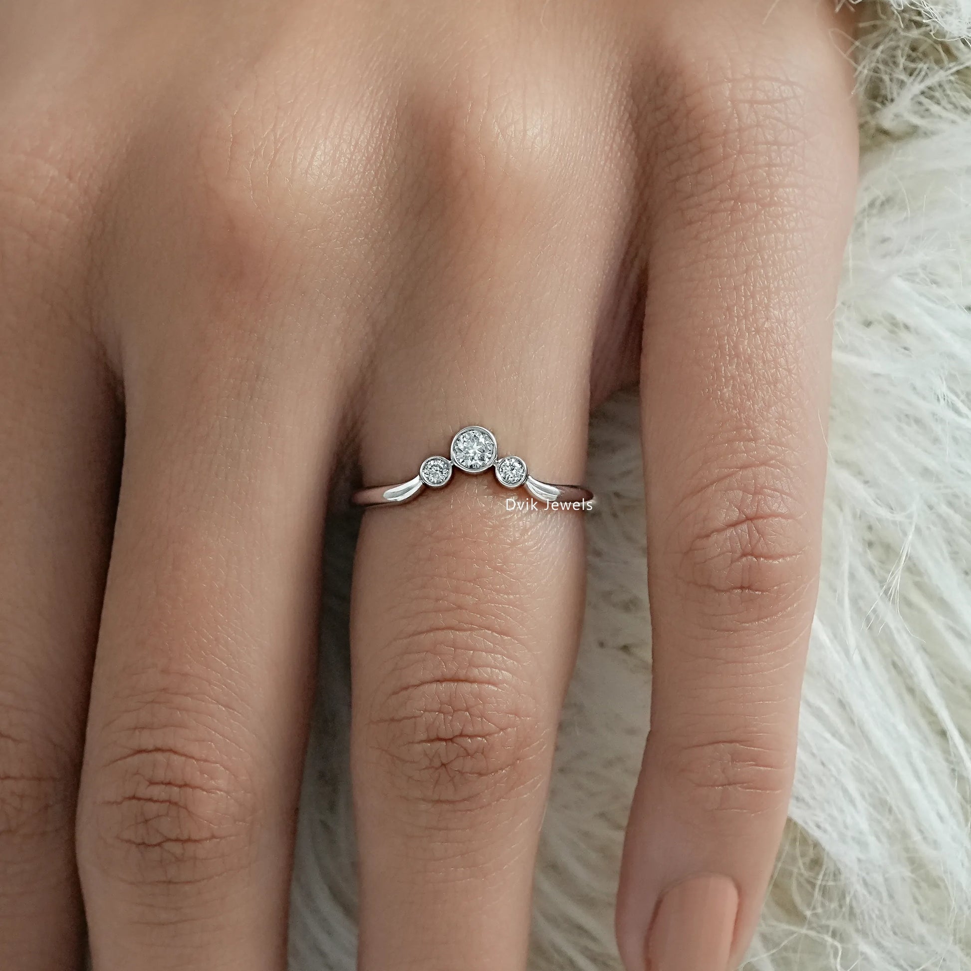 Three stone bezel ring worn on a finger for a modern bridal look.