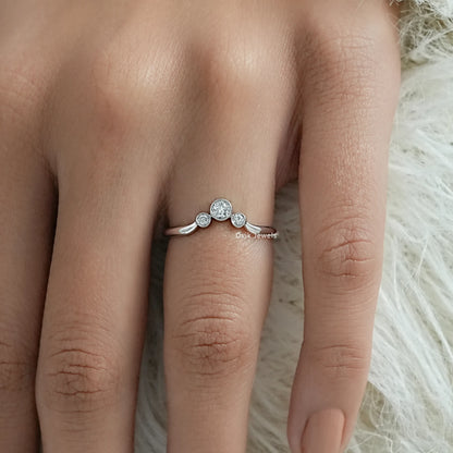 Three stone bezel ring worn on a finger for a modern bridal look.
