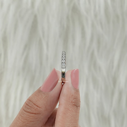 Side view of round diamond eternity band with open gallery holes held by women