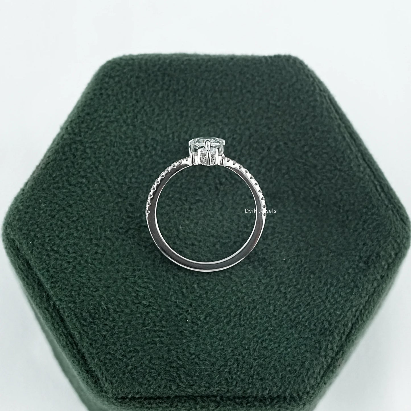 Side profile of pear diamond ring with round-shaped side stones and a delicate high-set basket