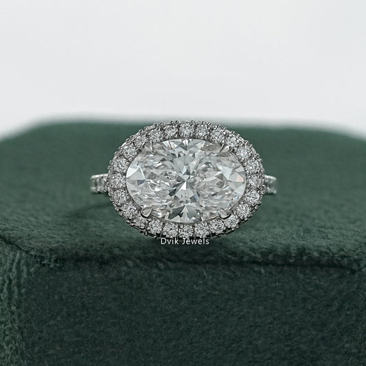 Halo engagement rings oval held to show the pave diamond border and shank