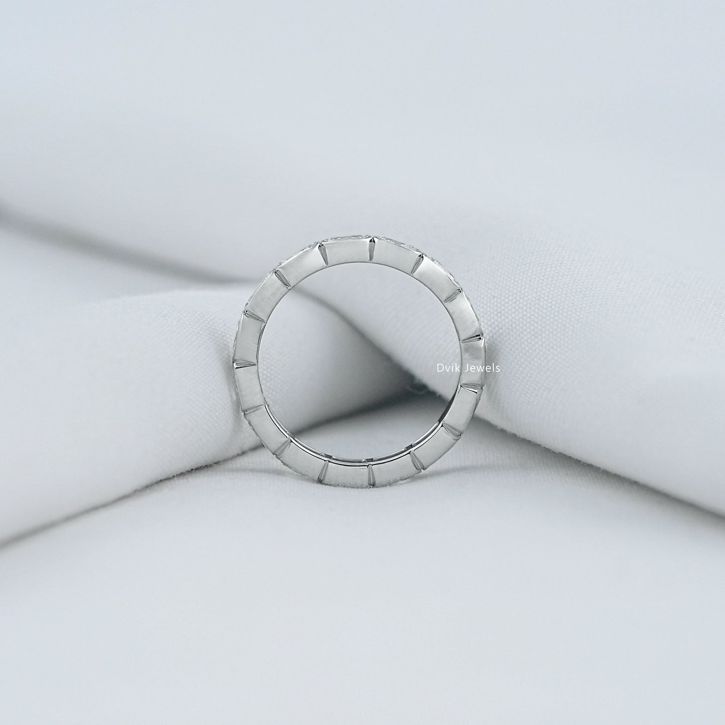 Radiant cut eternity band white gold finish on a soft fabric background