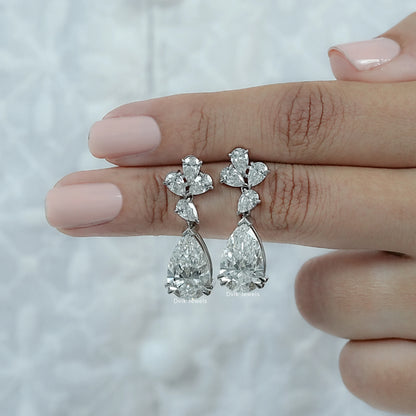 Lab Grown Diamond Pear Cut Floral Drop Earrings displayed between two fingers of woman
