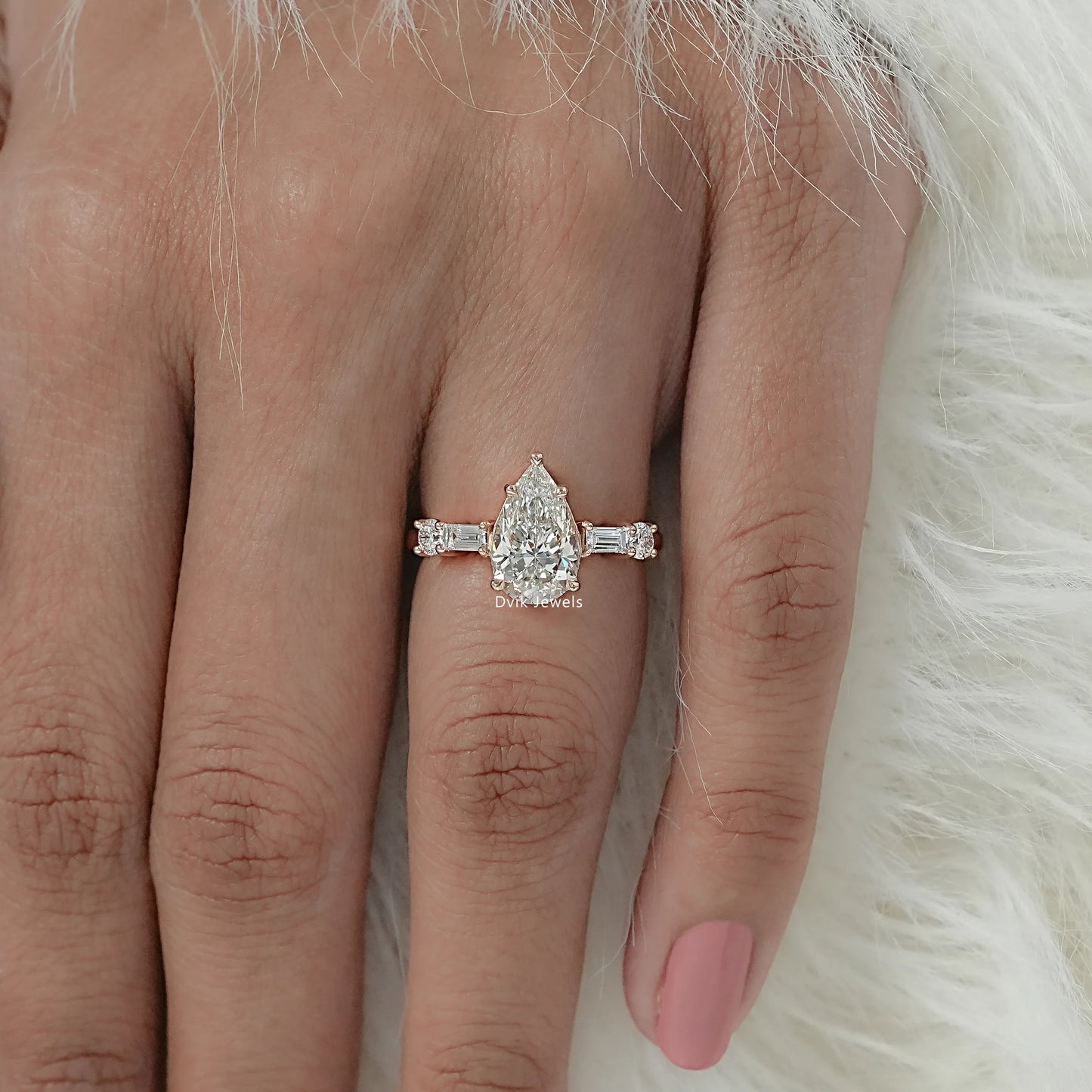 Five stone diamond ring with pear and baguette cut worn on a finger