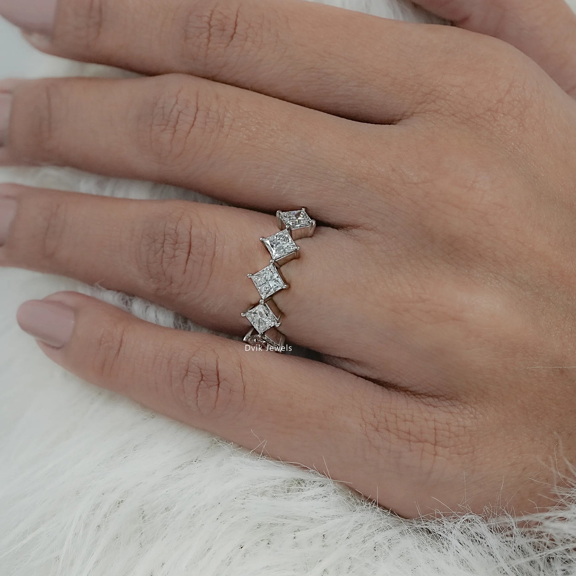 Angled view of floating diamond wedding bands on hand showcasing the unique kite-set stones.