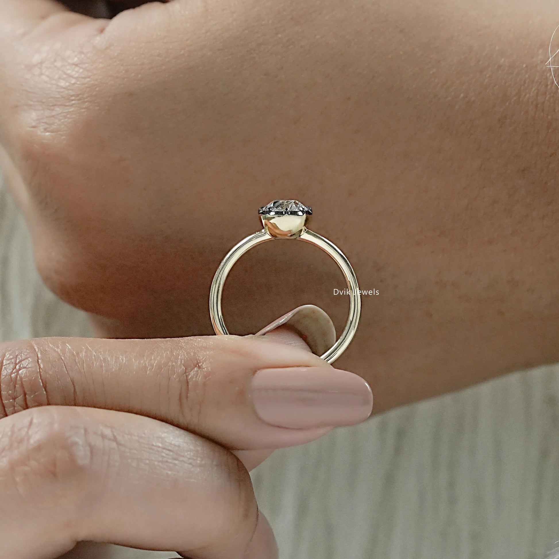 Round engagement ring with bezel held to show the brilliant sparkle