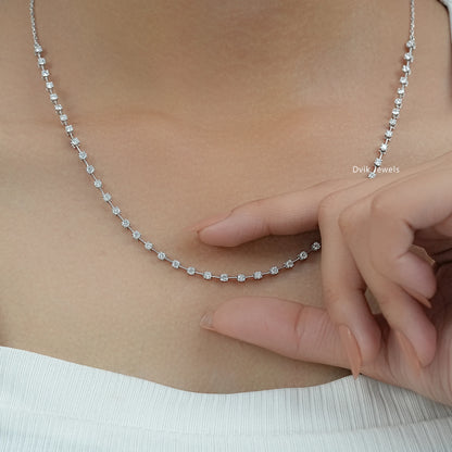 Tennis chain diamond necklace held to demonstrate its flexible gold link