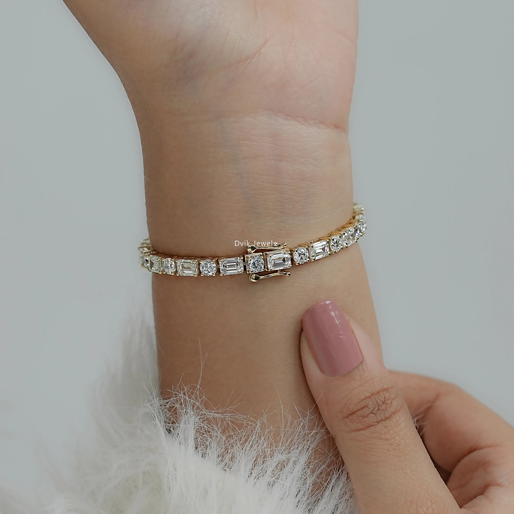 Woman wearing an round tennis bracelet with emerald cut diamond, showcasing prong settings