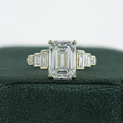 Elongated emerald cut engagement rings in 14k yellow gold on white fabric.