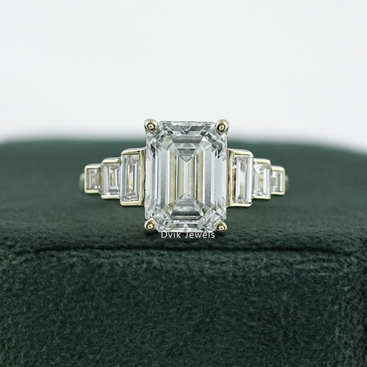 Elongated emerald cut engagement rings in 14k yellow gold on white fabric.