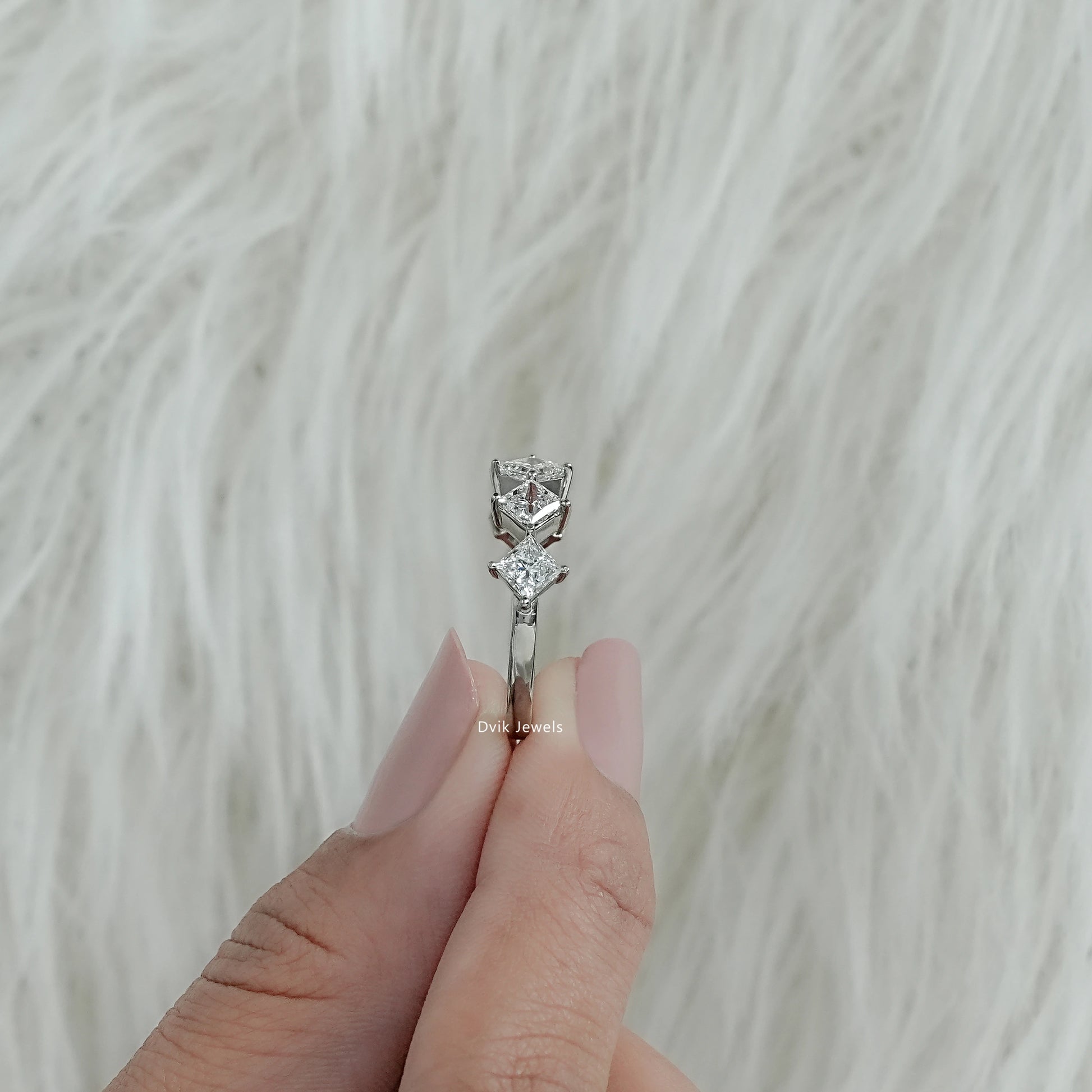 Bottom view of a five stone wedding band held between fingers showing the secure prong work.