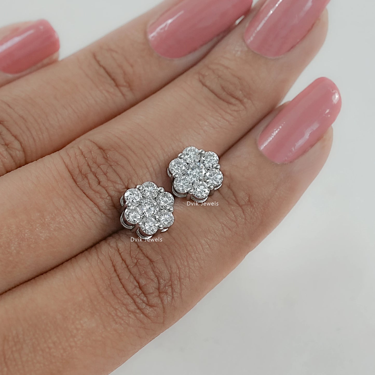 Round diamond floral stud earrings for women held between two fingers