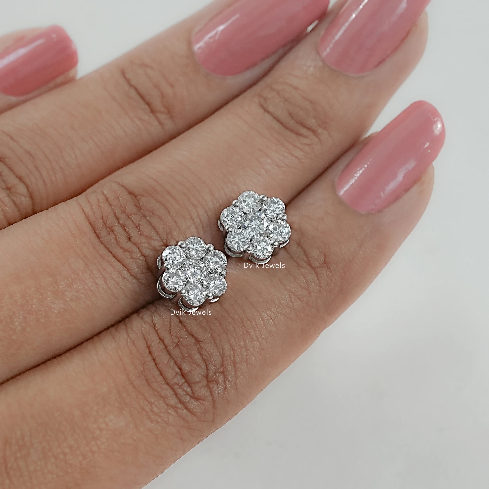 Round diamond floral stud earrings for women held between two fingers