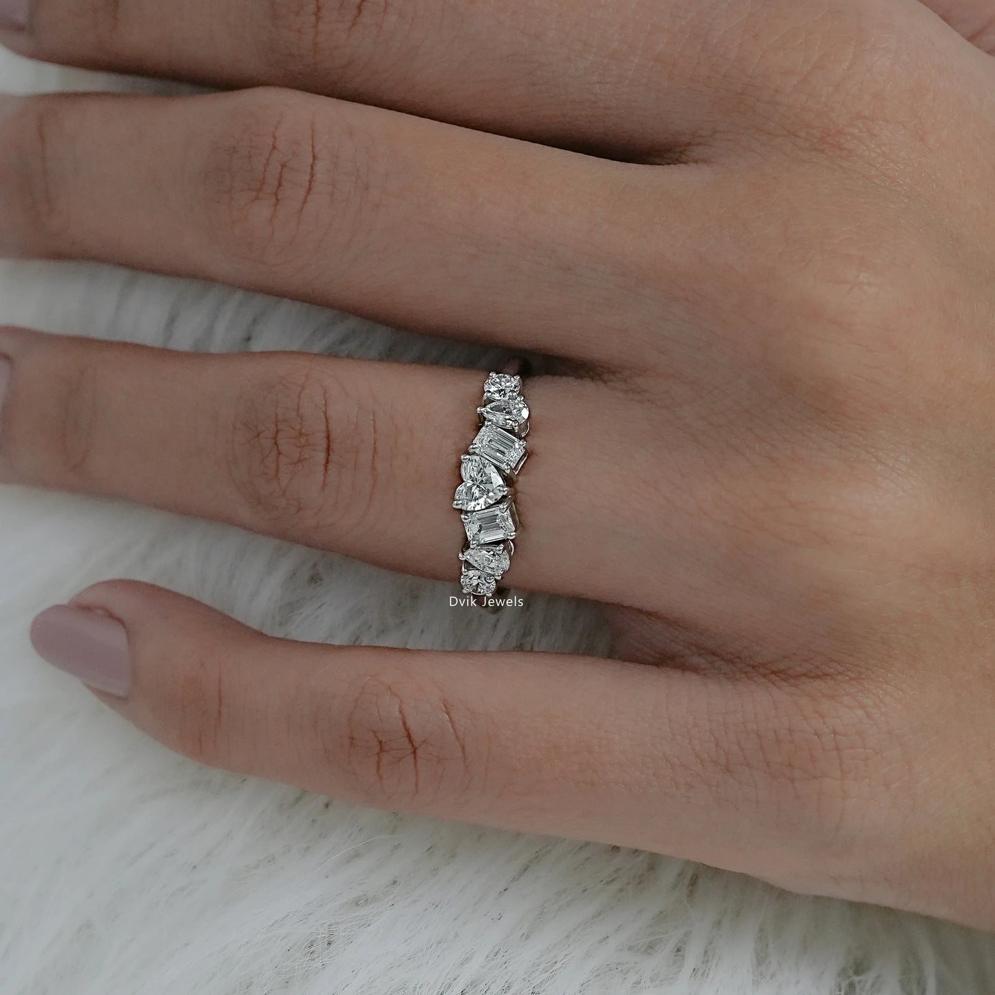 Angled hand view of a 7 stone diamond ring yellow gold showcasing heart and emerald cuts.