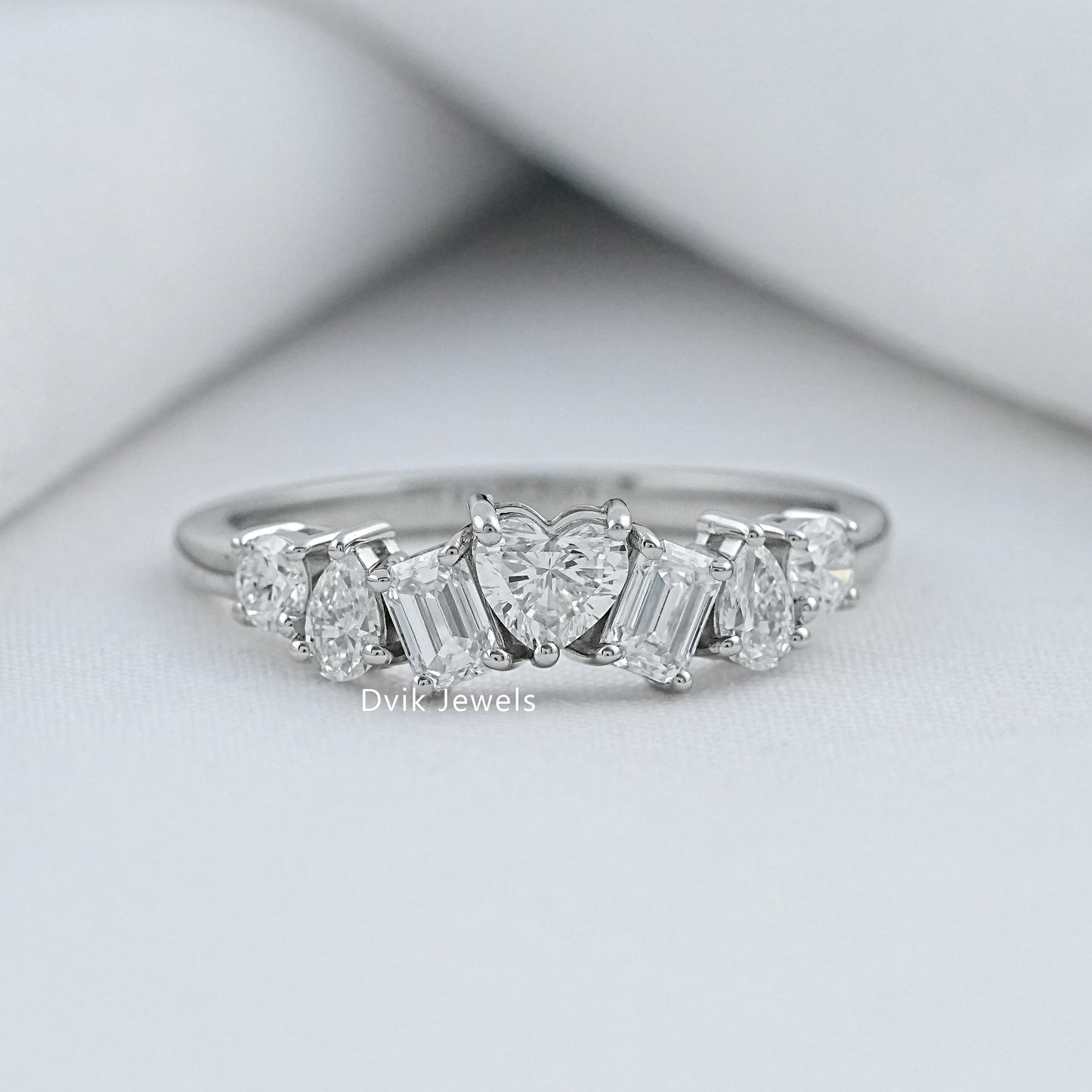 Dvik Jewels multi stone diamond rings front view on a soft white textured background.