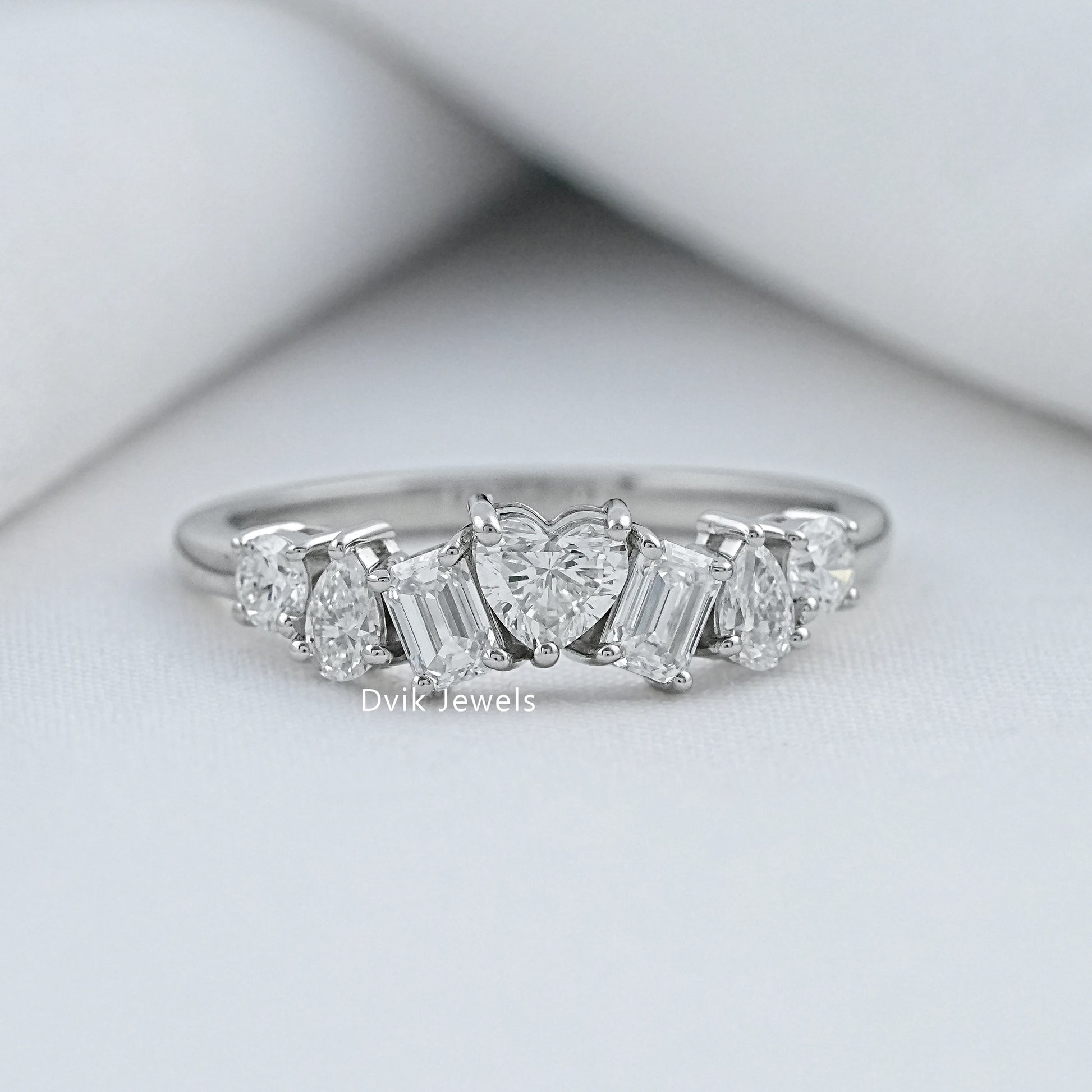 Dvik Jewels multi stone diamond rings front view on a soft white textured background.
