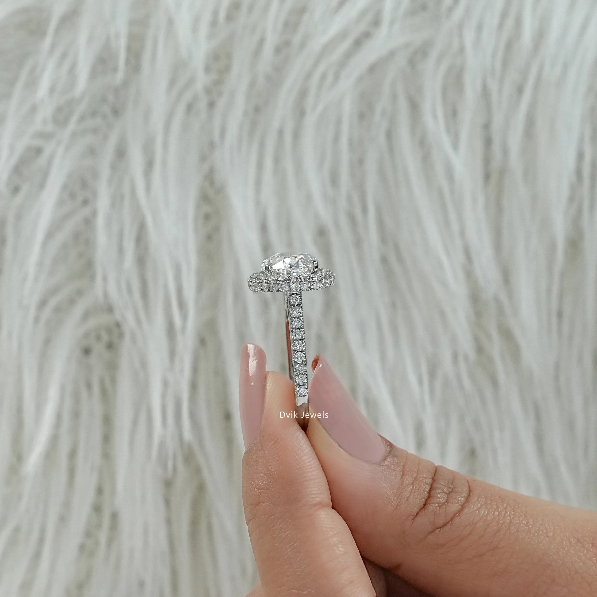 Oval lab diamond engagement ring held between fingers showing the side view