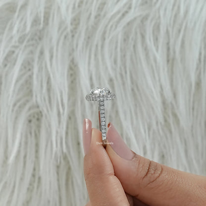 Oval lab diamond engagement ring held between fingers showing the side view