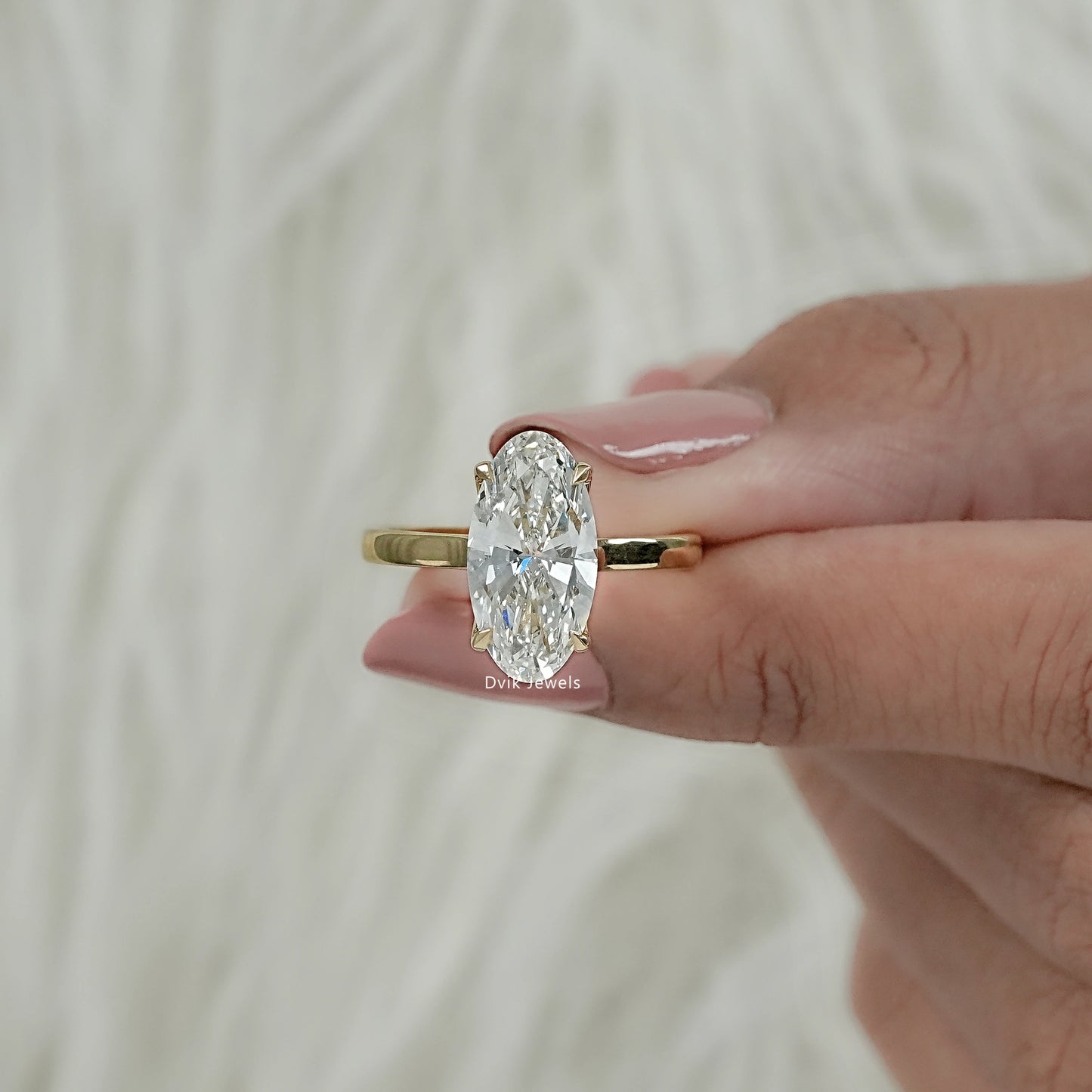 Front view of yellow gold hidden halo engagement ring with moval cut hold by women hand