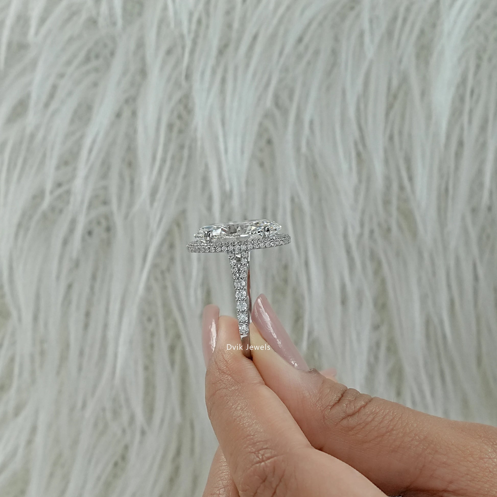 Oval diamond ring with halo worn on a hand highlighting the center stone