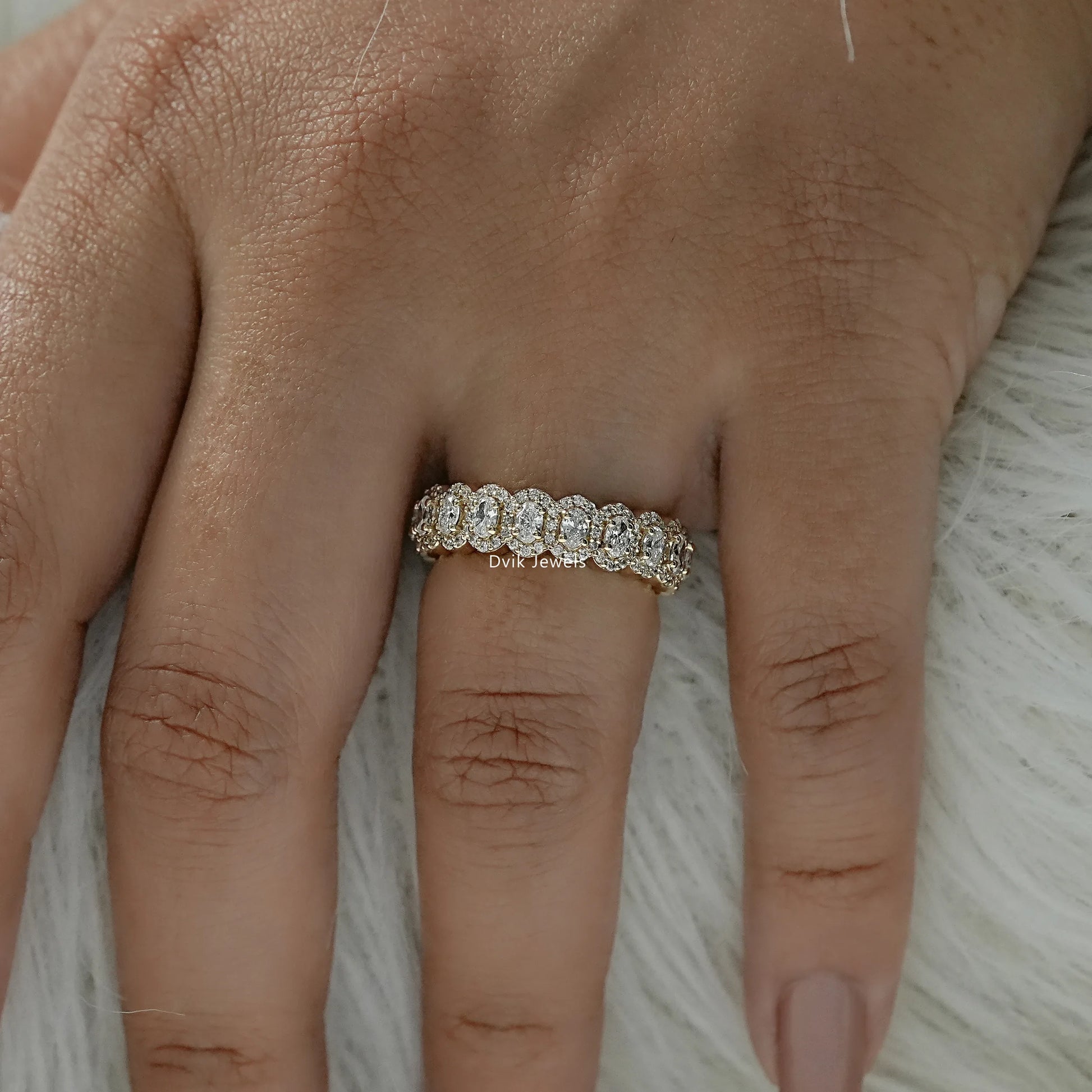 Oval halo eternity band worn as a luxury bridal diamond ring.