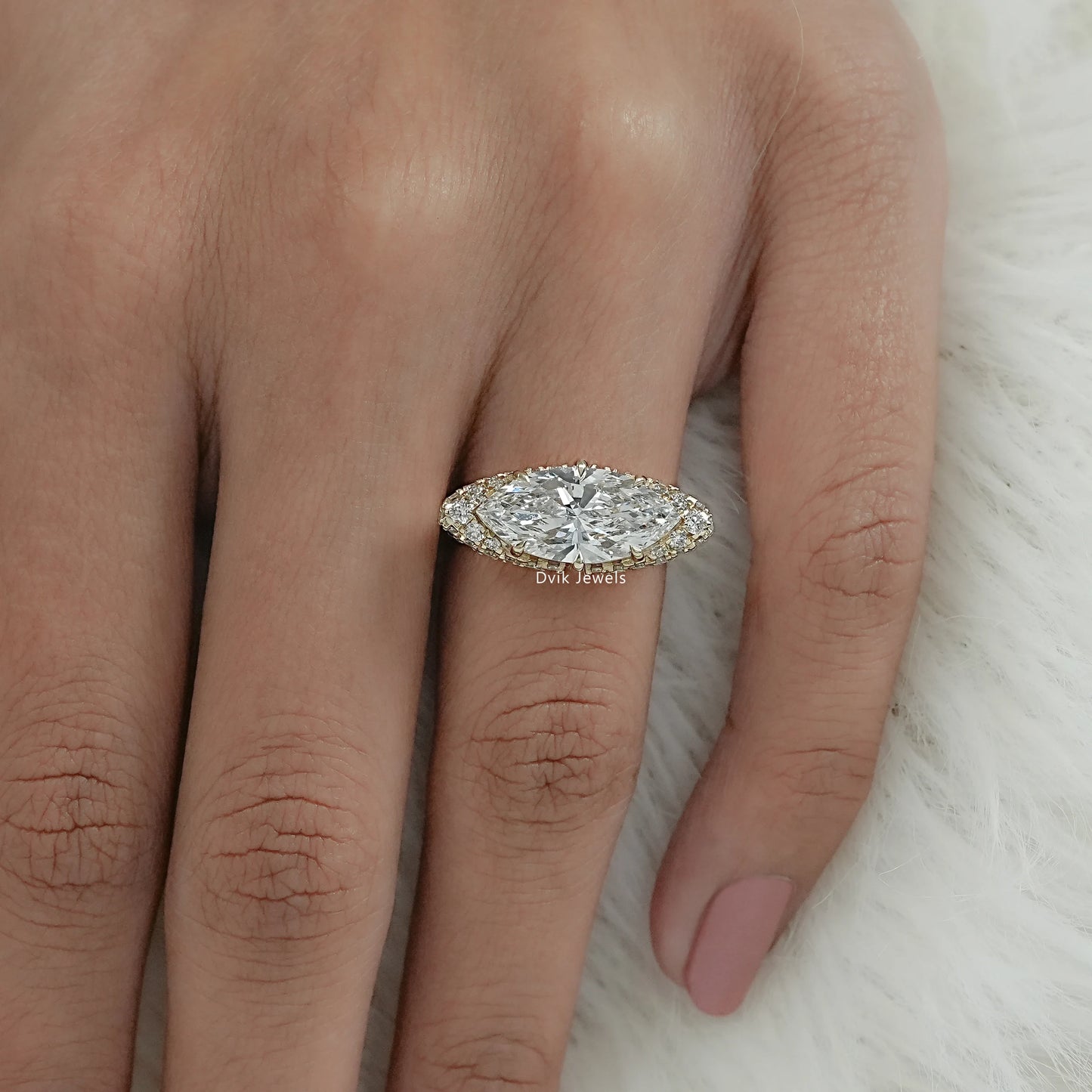 Elongated marquise cut engagement ring on finger, highlighting the pave diamond accents