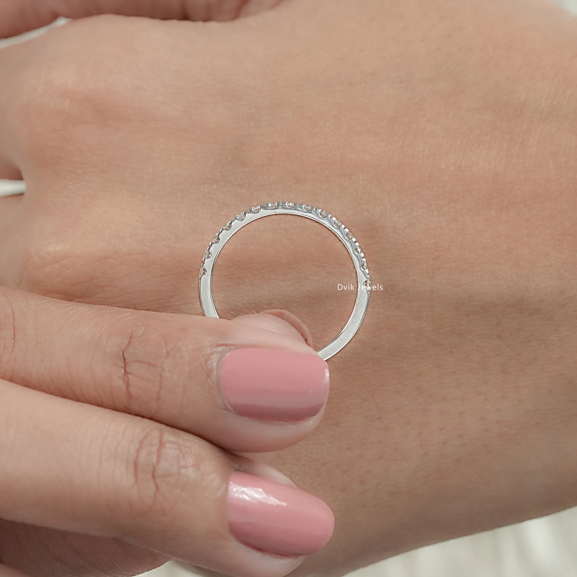 Minimal round diamond half eternity wedding band held by women for middle view