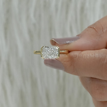 Unique radiant cut engagement rings yellow gold bezel held in hand