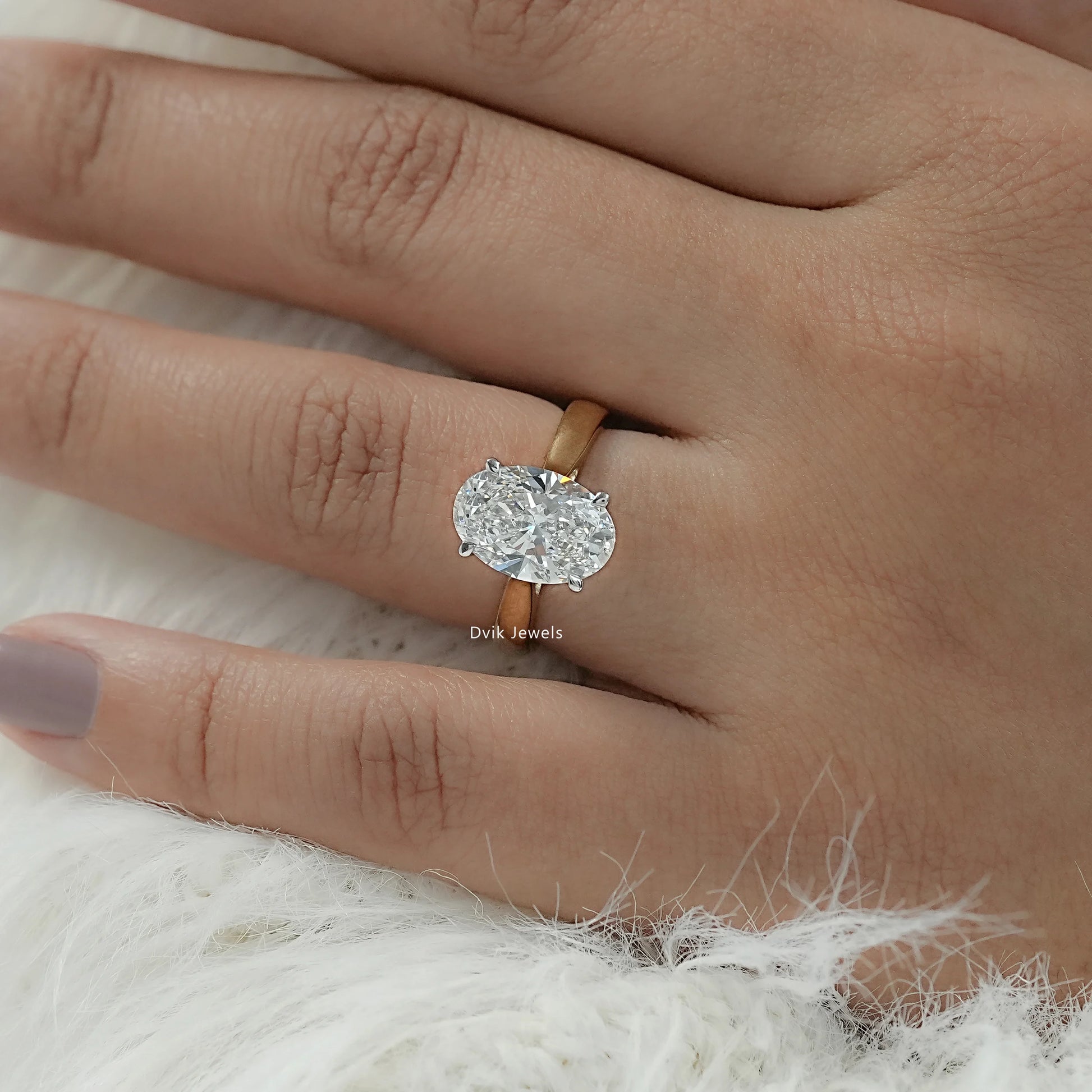 Close-up view of an oval engagement ring with hidden halo detailing underneath the center stone.