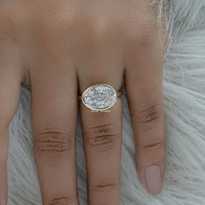 East west oval bezel ring yellow gold lab diamond on hand top view