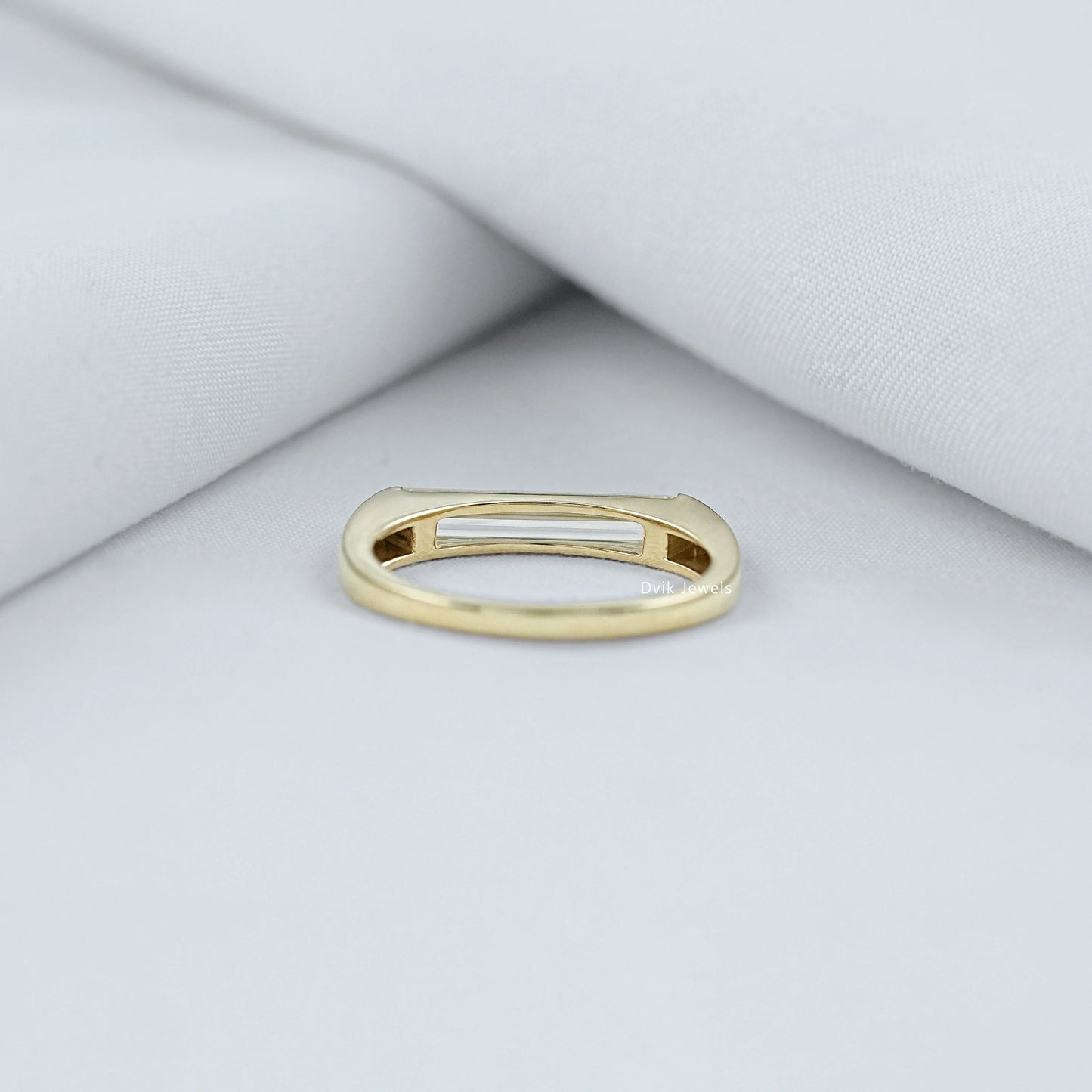 Baguette diamond engagement ring held to show the high quality metal band