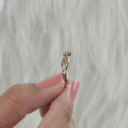 Minimal pear diamond curved wavy ring in yellow gold held by women for side angle