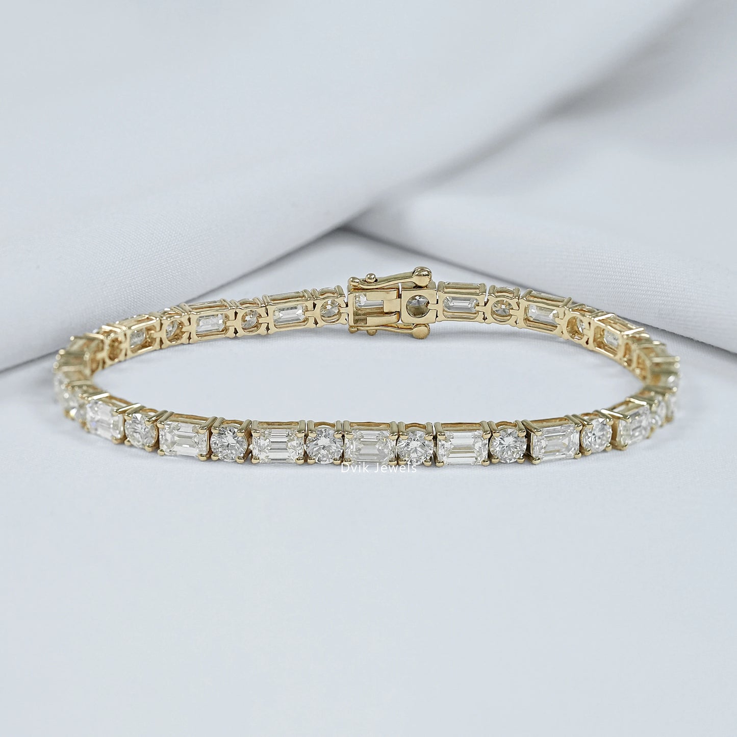 Emerald and round cut lab diamond tennis bracelet on luxury jewelry box by Dvik Jewels