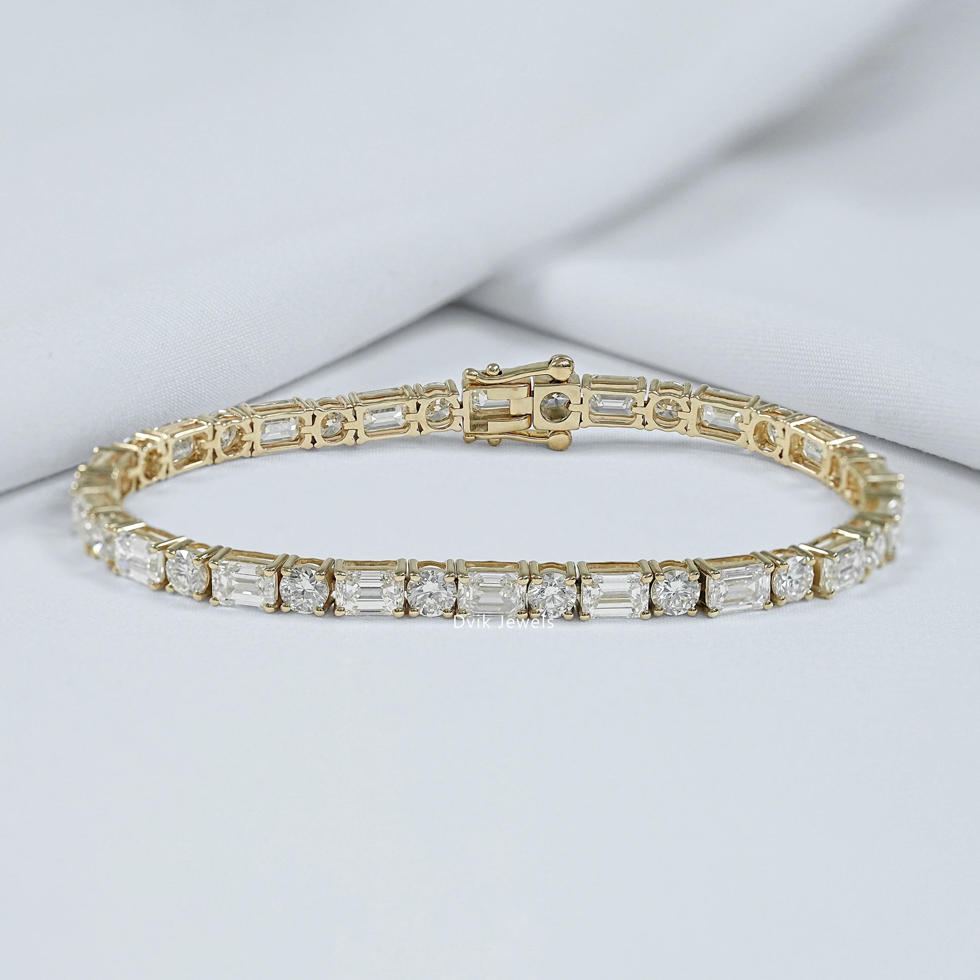 Emerald and round cut lab diamond tennis bracelet on luxury jewelry box by Dvik Jewels