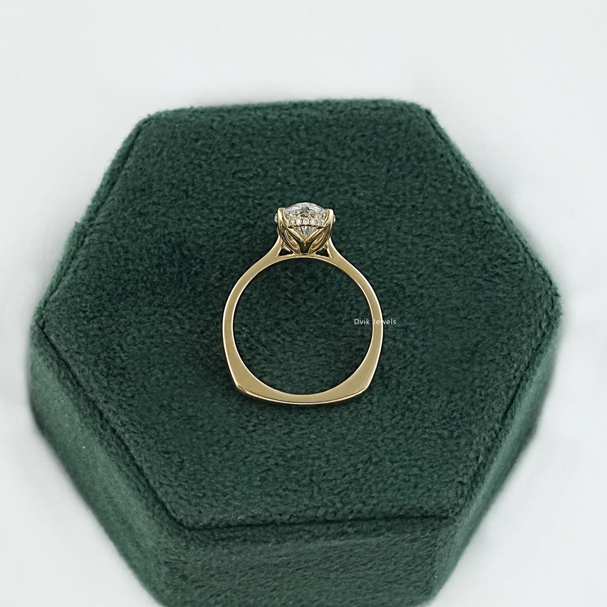 Moval cut hidden halo ring on jewelry box showing 14K yellow gold band