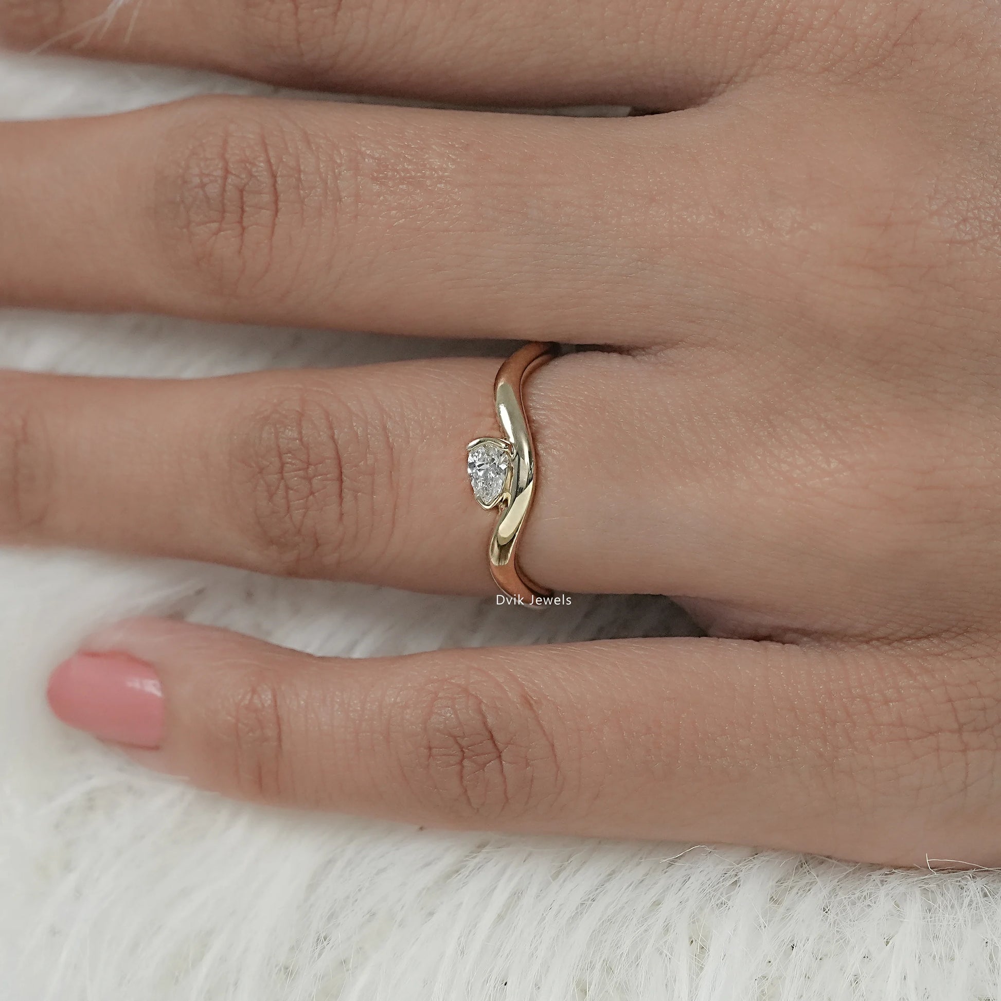 Pear cut engagement ring with wave/curved contour band on model hand