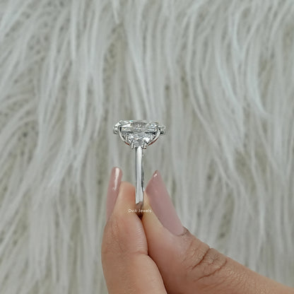 Oval engagement ring with half moon side stones on a soft fabric close-up