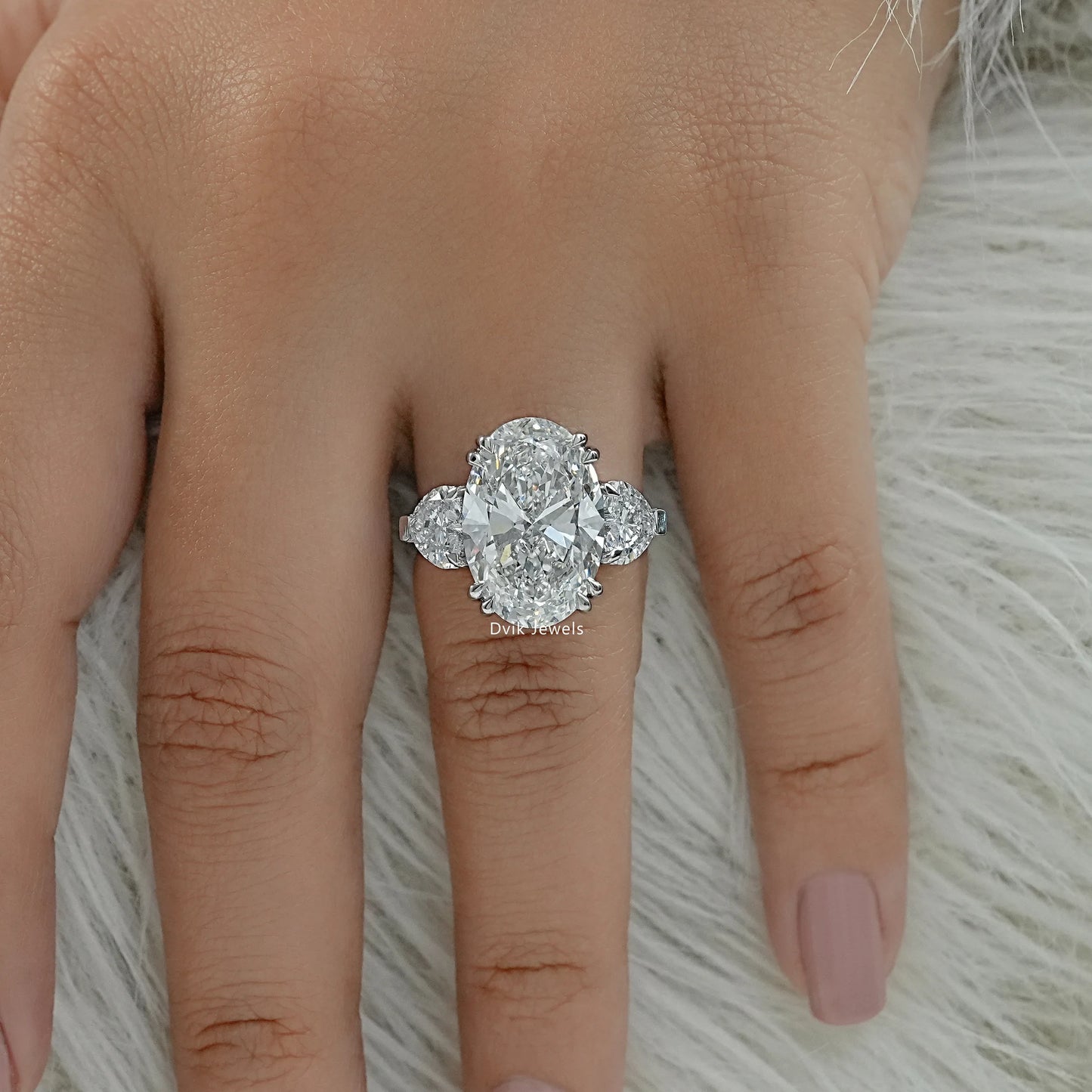 Three stone oval diamond engagement ring on finger top view